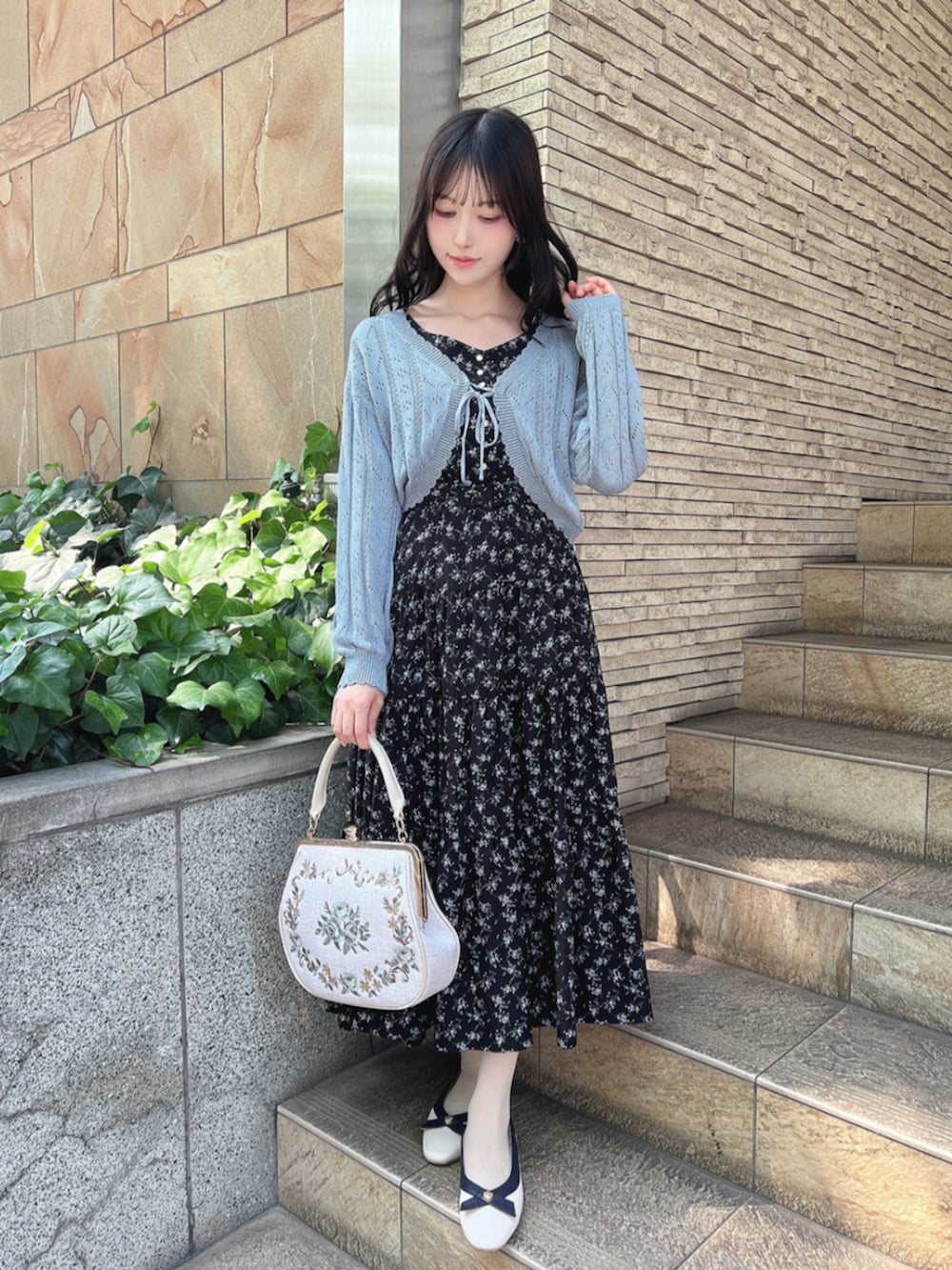 ホワイト系のパンプス、ホワイト系のハンドバッグ、ブラック系のワンピースを着用したレディースの夏コーディネートの2枚目の写真