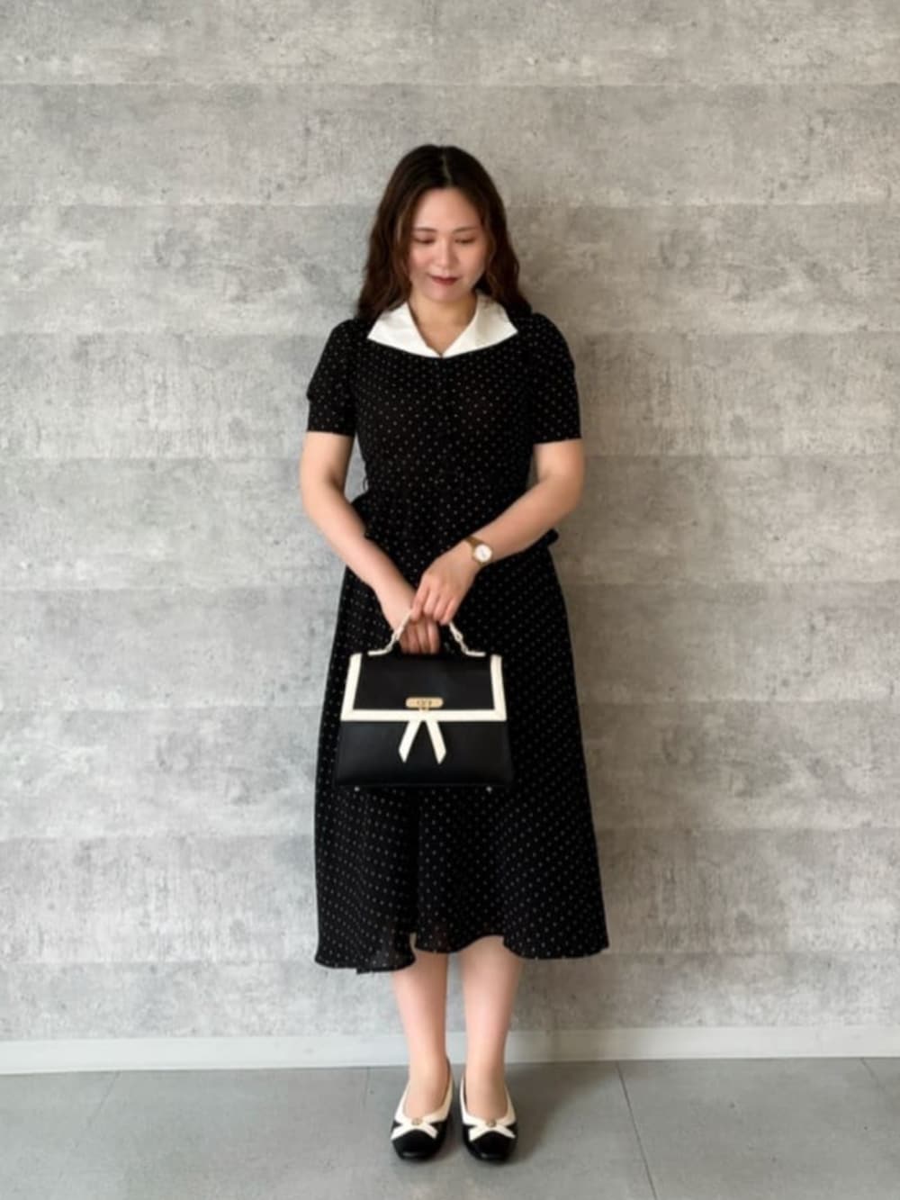 ブラック系のハンドバッグ、ブラック系のパンプス、ブラック系のワンピースを着用したレディースの夏コーディネートの2枚目の写真