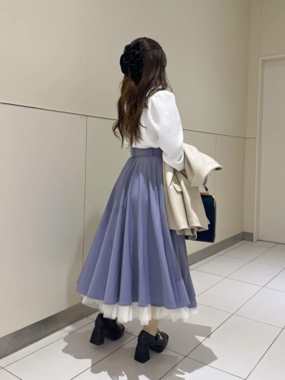 ブラック系のパンプス、ブルー系のハンドバッグ、ベージュ系のテーラードジャケットを着用したレディースの冬コーディネートの2枚目の写真