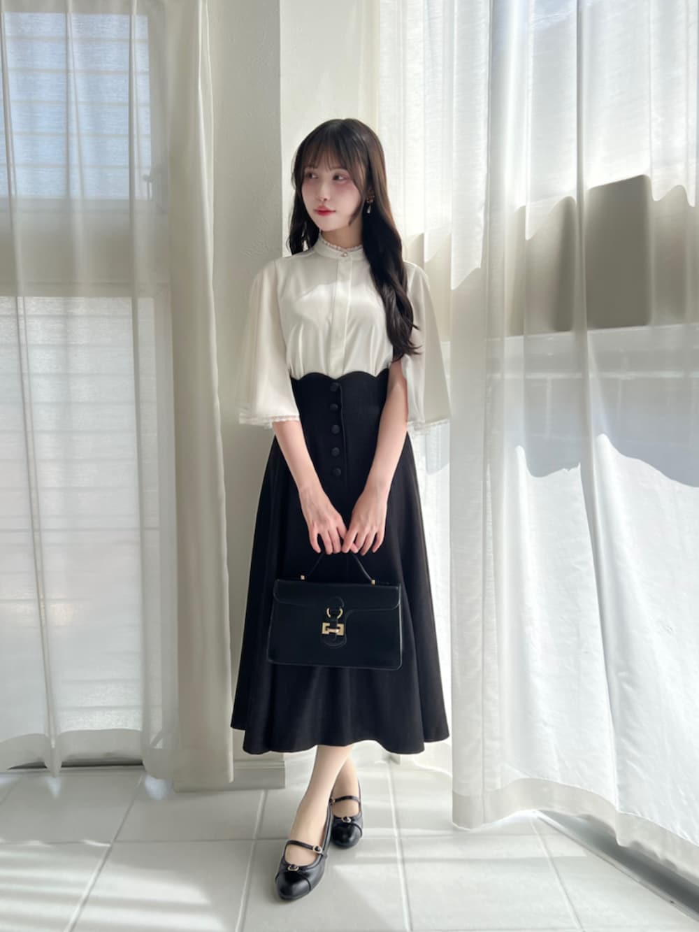 ブラック系のハンドバッグ、ブラック系のデニムスカート、ホワイト系のシャツ/ブラウスを着用したレディースの夏コーディネートの3枚目の写真