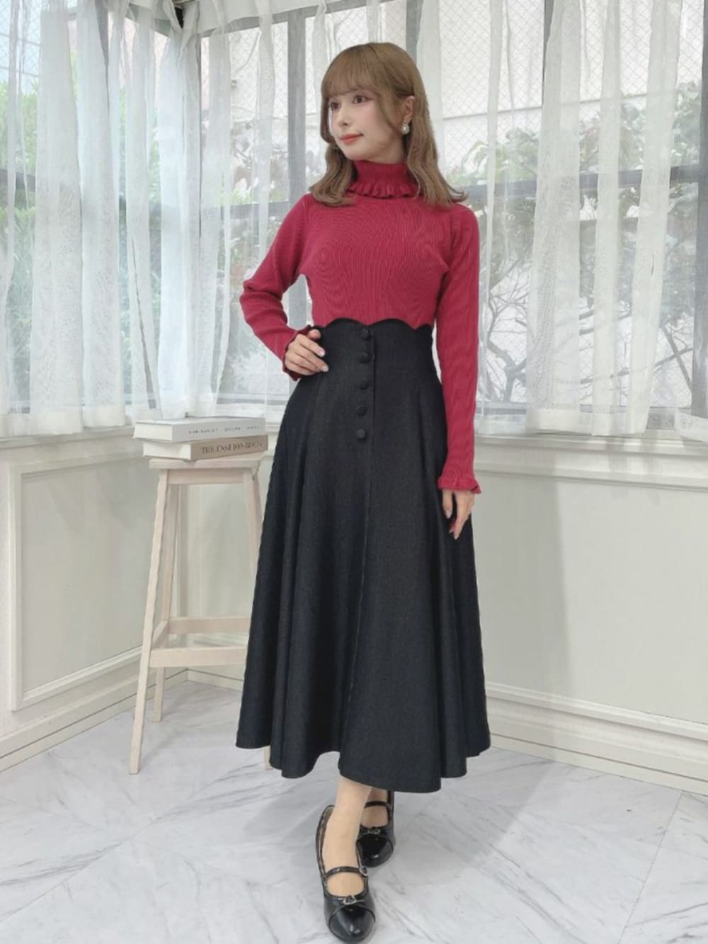 ブラック系のデニムスカート、ブラック系のパンプス、レッド系のニット/セーターを着用したレディースの冬コーディネートの2枚目の写真