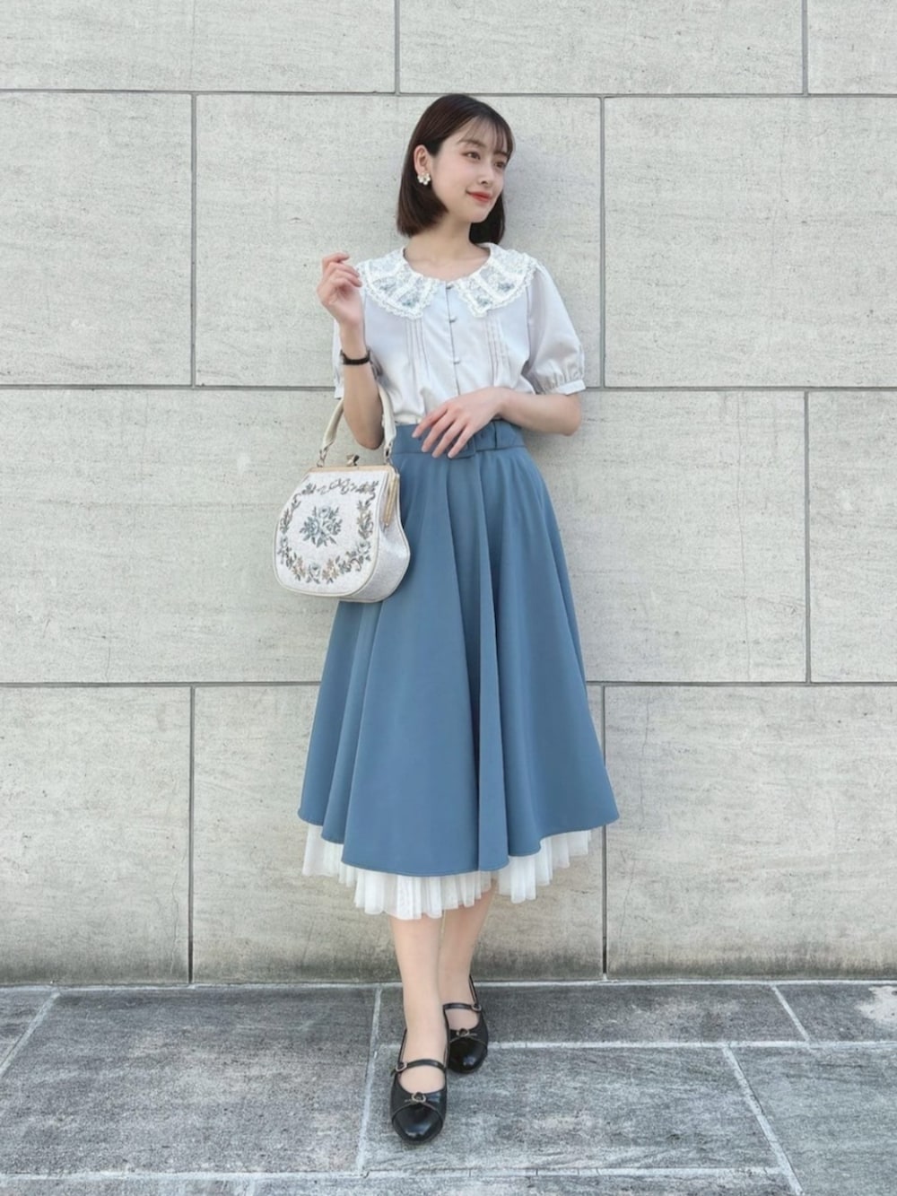 ブルー系のスカート、ホワイト系のハンドバッグ、グレー系のシャツ/ブラウスを着用したレディースの夏コーディネートの2枚目の写真
