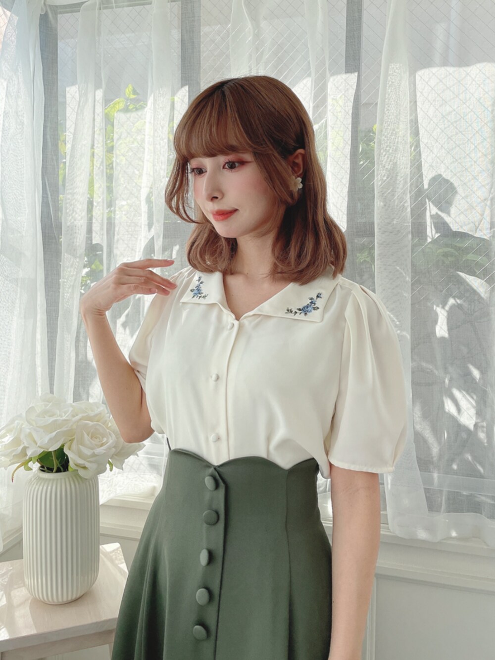 ホワイト系のシャツ/ブラウス、グリーン系のスカート、ブラック系のパンプスを着用したレディースの秋コーディネートの2枚目の写真