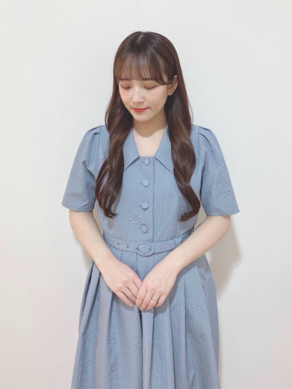 ブラック系のハンドバッグ、ブラック系のパンプス、ブルー系のワンピースを着用したレディースの春コーディネートの2枚目の写真