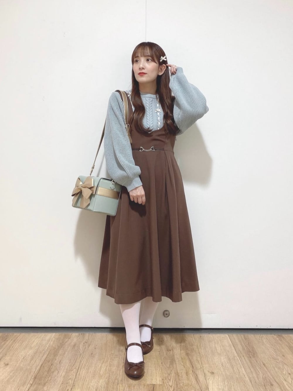 ブラウン系のジャンパースカート、ブラウン系のバレエシューズ、グリーン系のショルダーバッグを着用したレディースの冬コーディネートの2枚目の写真