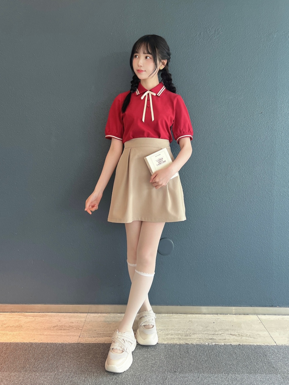 ホワイト系のスニーカー、ベージュ系のスカート、レッド系のポロシャツを着用したレディースの春コーディネートの2枚目の写真
