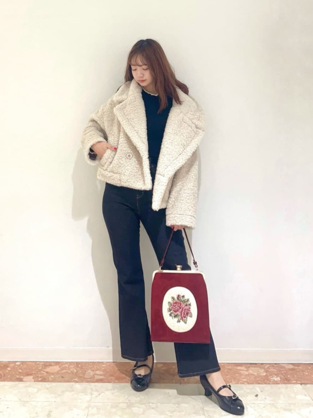 ブラック系のパンプス、ブラック系のデニムパンツ、レッド系のハンドバッグを着用したレディースの冬コーディネートの2枚目の写真