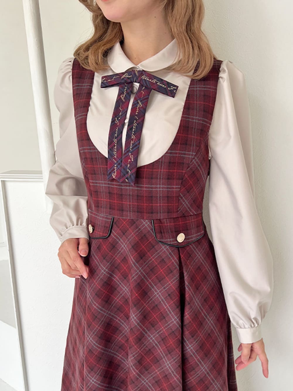 レッド系のジャンパースカート、ブラウン系のバレエシューズ、ベージュ系のシャツ/ブラウスを着用したレディースの冬コーディネートの4枚目の写真