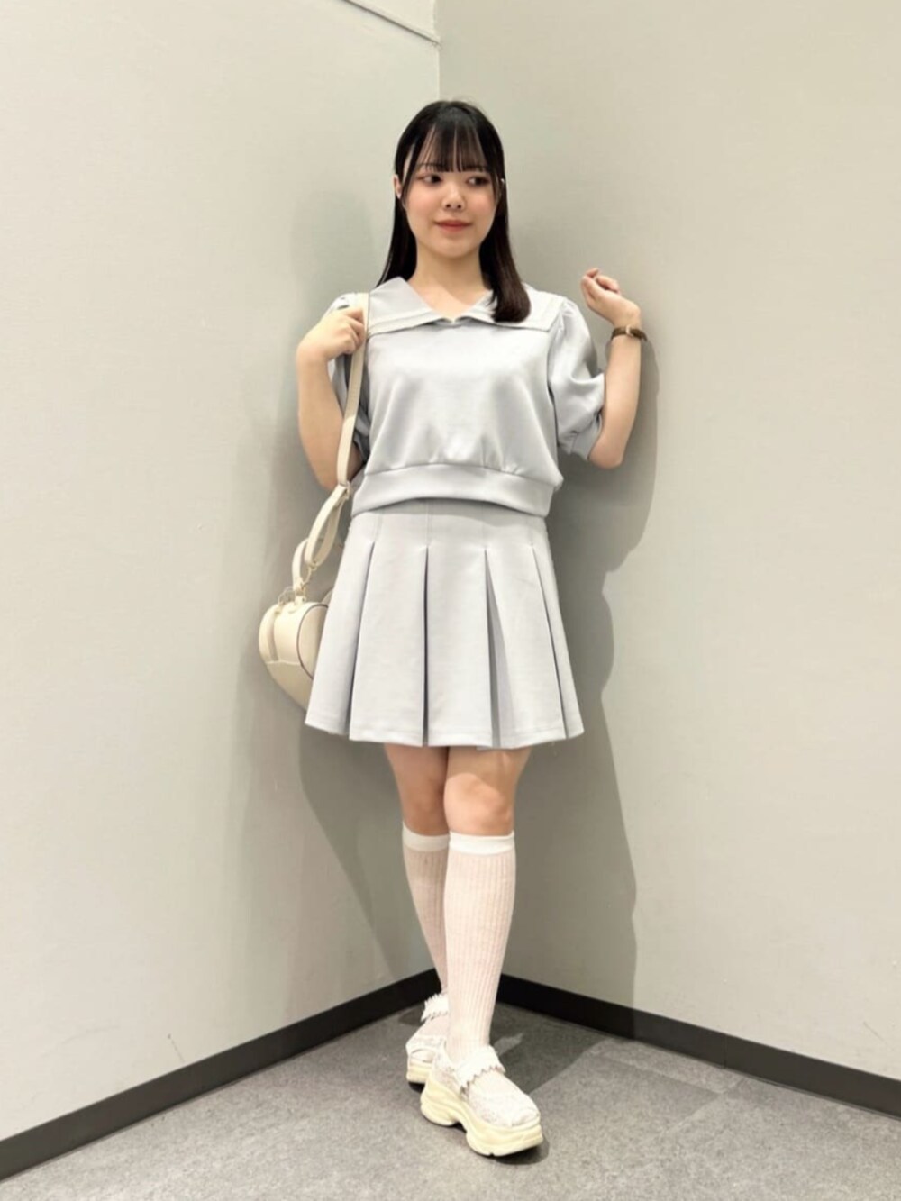 ブルー系のスカート、ホワイト系のハンドバッグ、ホワイト系のサンダルを着用したレディースの夏コーディネートの2枚目の写真