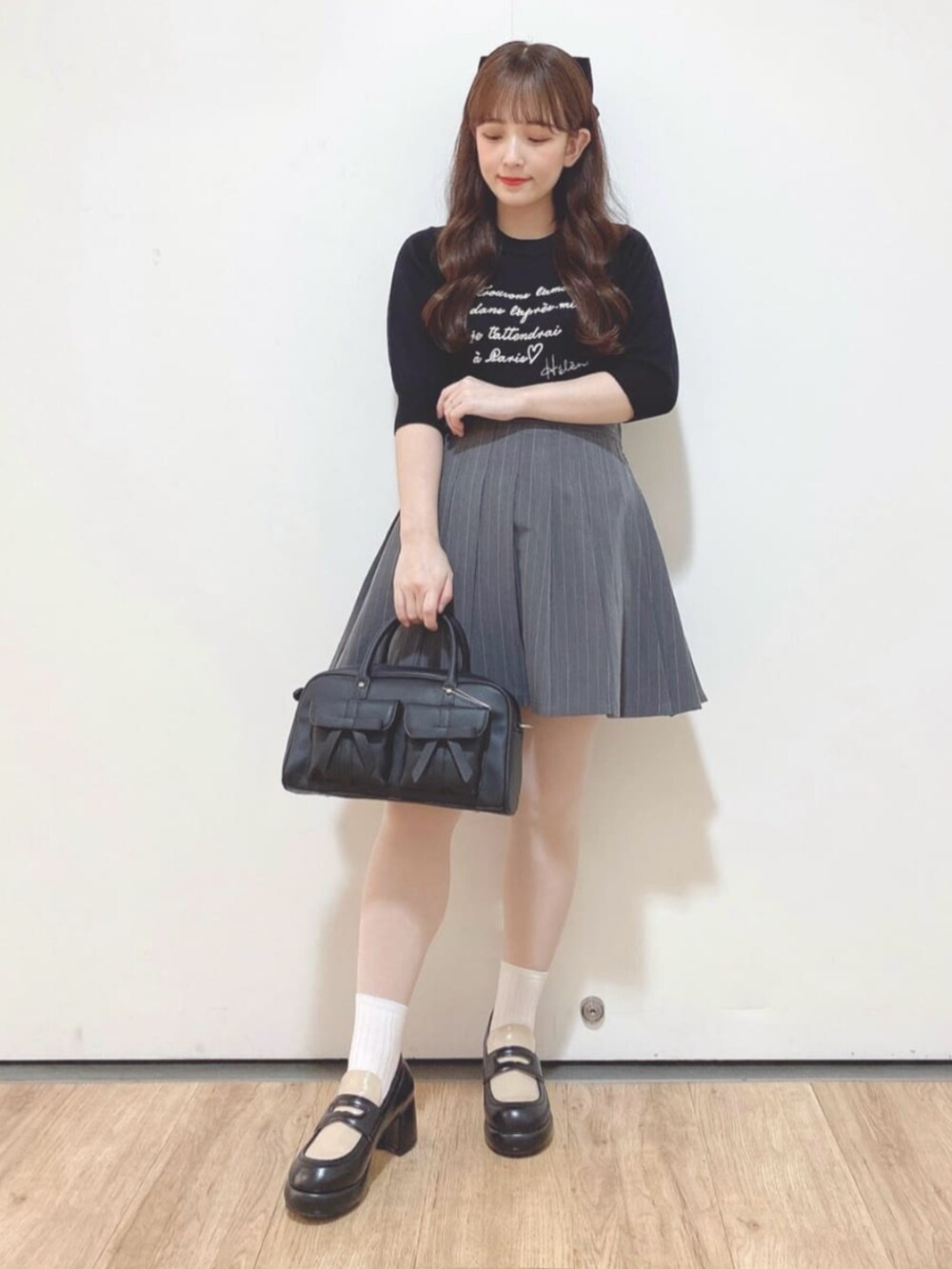 グレー系のスカート、ブラック系のハンドバッグ、ブラック系のローファーを着用したレディースの秋コーディネートの3枚目の写真