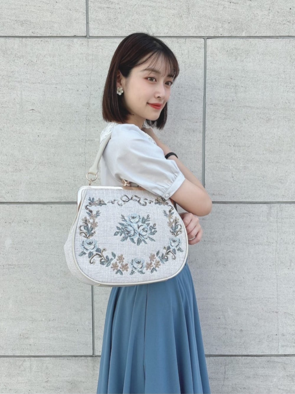 ブルー系のスカート、ホワイト系のハンドバッグ、グレー系のシャツ/ブラウスを着用したレディースの夏コーディネートの3枚目の写真