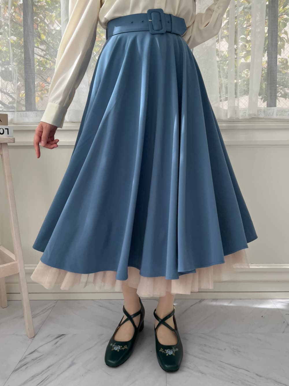 ブルー系のスカート、ホワイト系のシャツ/ブラウス、ブルー系のパンプスを着用したレディースの秋コーディネートの2枚目の写真