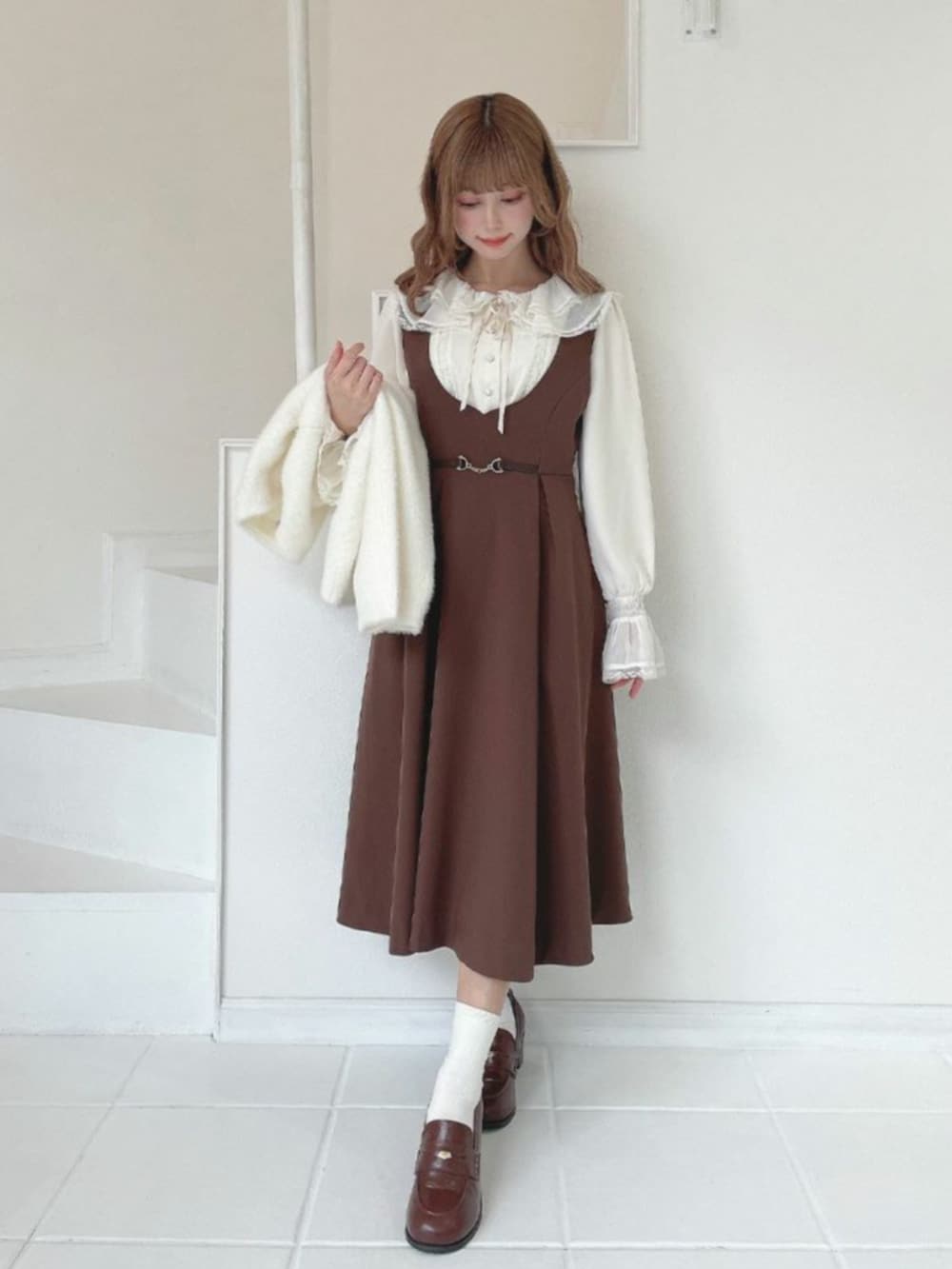 ブラウン系のジャンパースカート、ブラウン系のローファー、ホワイト系のシャツ/ブラウスを着用したレディースの冬コーディネートの2枚目の写真