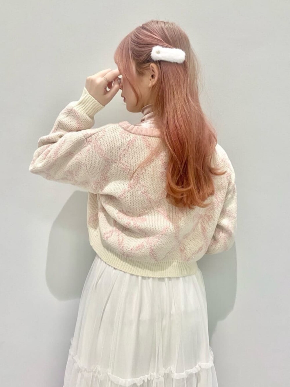 ピンク系のハンドバッグ、ブラウン系のブーツ、ピンク系のニット/セーターを着用したレディースの冬コーディネートの2枚目の写真