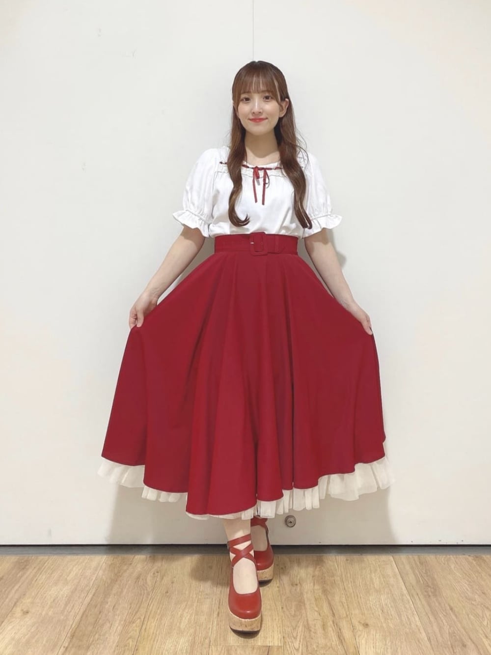 レッド系のパンプス、レッド系のハンドバッグ、レッド系のスカートを着用したレディースの夏コーディネートの3枚目の写真