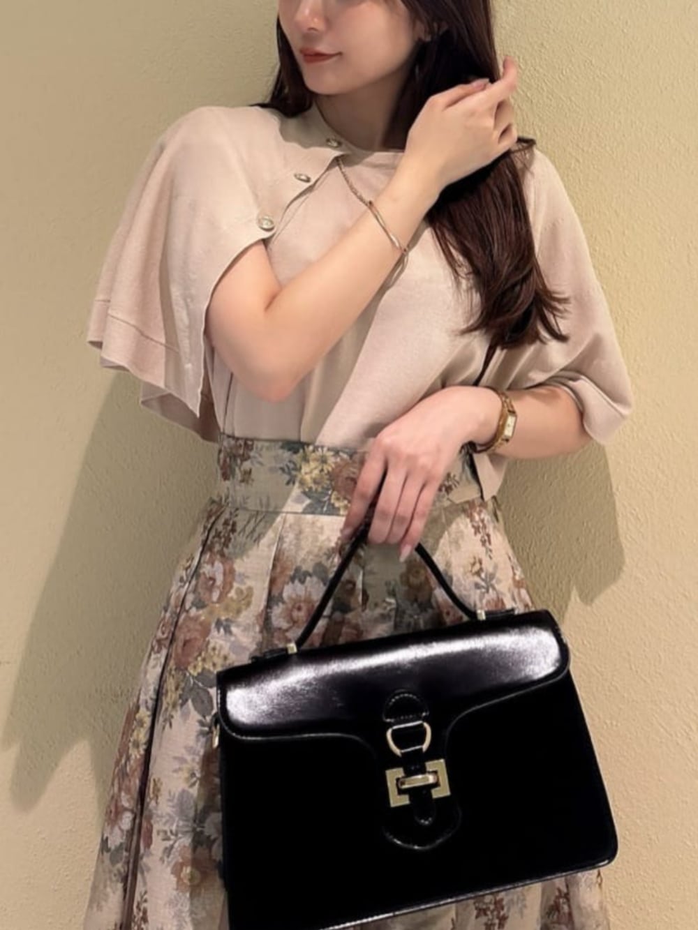 ブラック系のハンドバッグ、ブラック系のパンプス、ベージュ系のスカートを着用したレディースの秋コーディネートの2枚目の写真