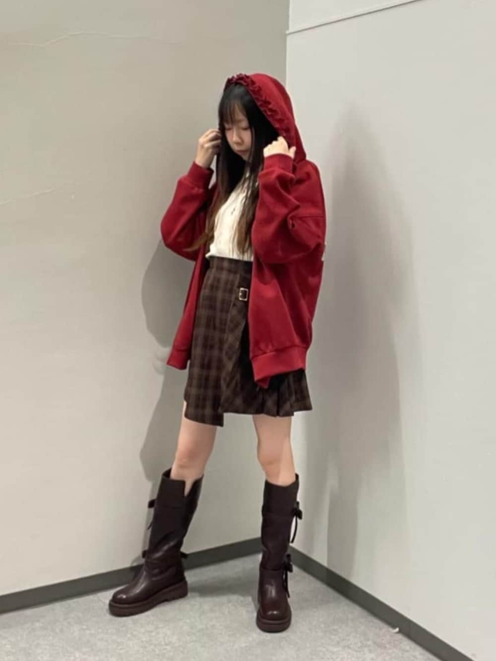 ブラウン系のスカート、レッド系のパーカー、ブラウン系のブーツを着用したレディースの秋コーディネートの2枚目の写真