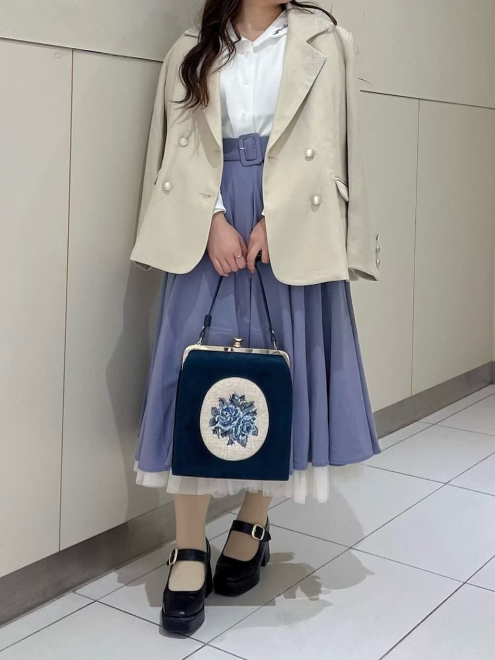 ブラック系のパンプス、ブルー系のハンドバッグ、ベージュ系のテーラードジャケットを着用したレディースの冬コーディネートの3枚目の写真