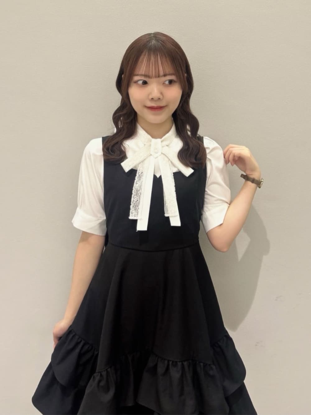 ブラック系のパンプス、ホワイト系のシャツ/ブラウス、ブラック系のジャンパースカートを着用したレディースの春コーディネートの3枚目の写真