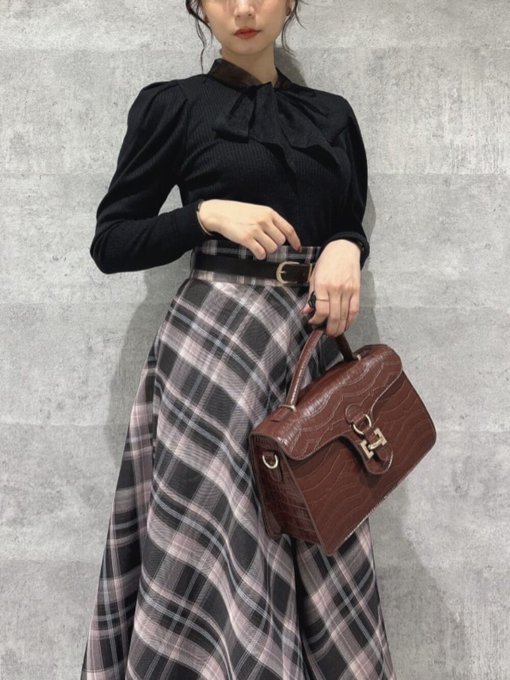 ブラウン系のスカート、レッド系のパンプス、イエロー系のハンドバッグを着用したレディースの秋コーディネートの2枚目の写真