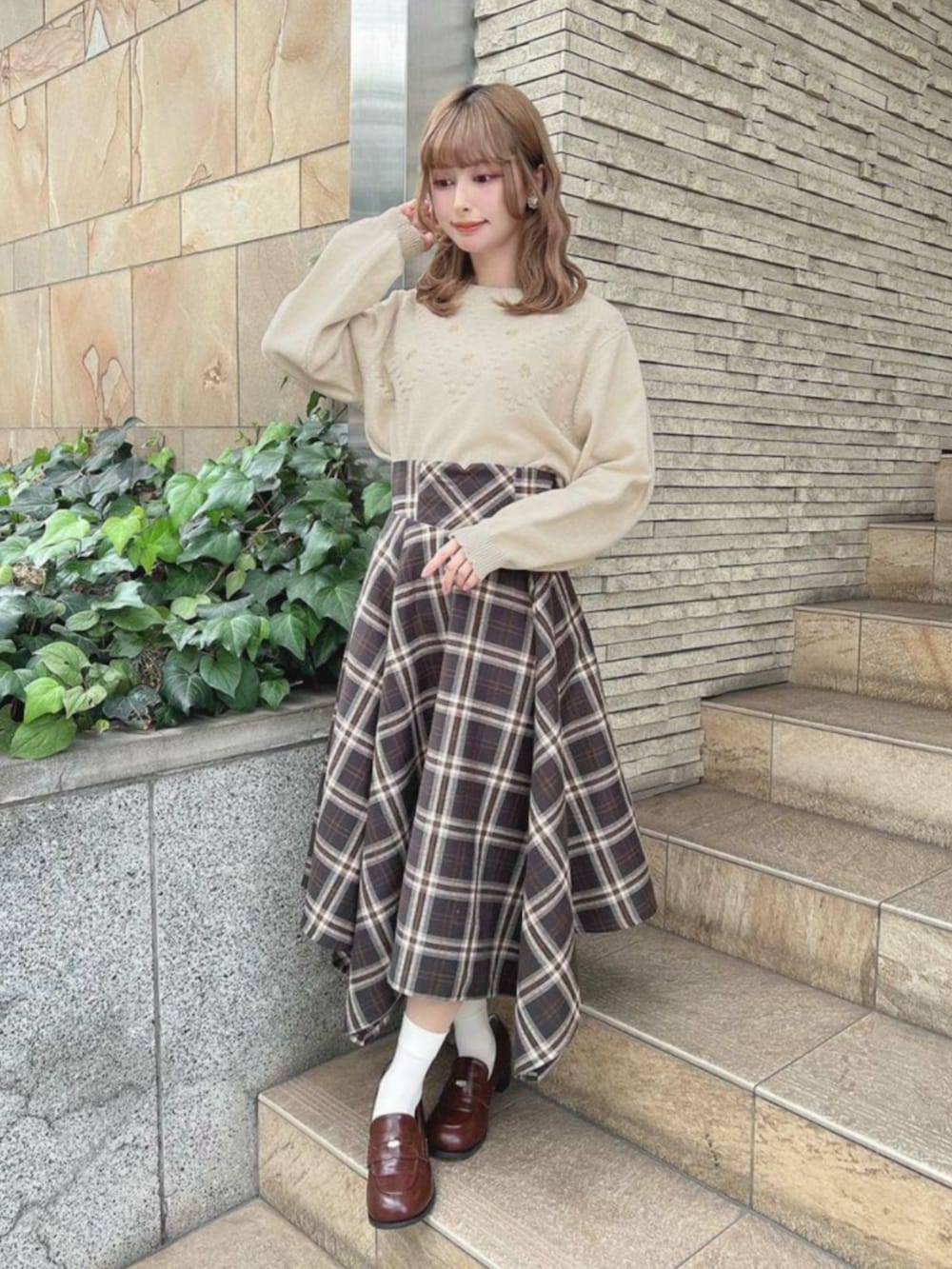 ブラウン系のローファー、ブラック系のスカート、ベージュ系のニット/セーターを着用したレディースの冬コーディネートの2枚目の写真