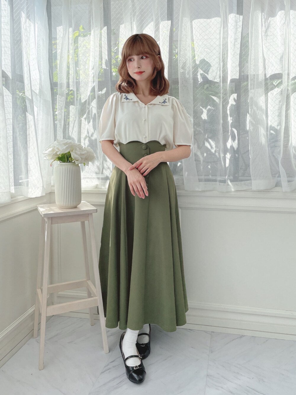 ホワイト系のシャツ/ブラウス、グリーン系のスカート、ブラック系のパンプスを着用したレディースの秋コーディネートの3枚目の写真