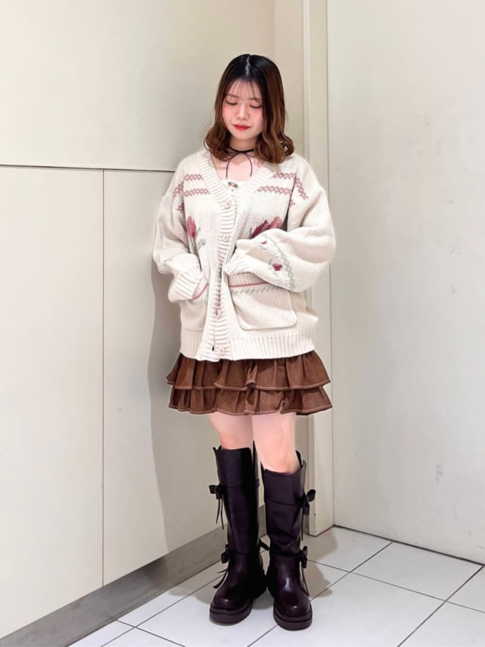 ブラウン系のスカート、ブラウン系のブーツ、ピンク系のカーディガン/ボレロを着用したレディースの秋コーディネートの2枚目の写真