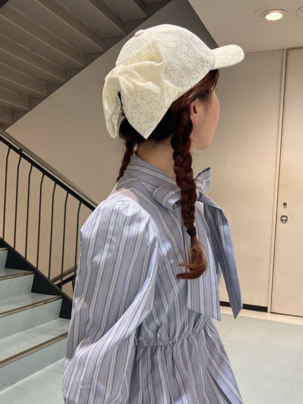 グレー系のワンピース、ホワイト系のサンダル、ホワイト系のキャップを着用したレディースの春コーディネートの3枚目の写真