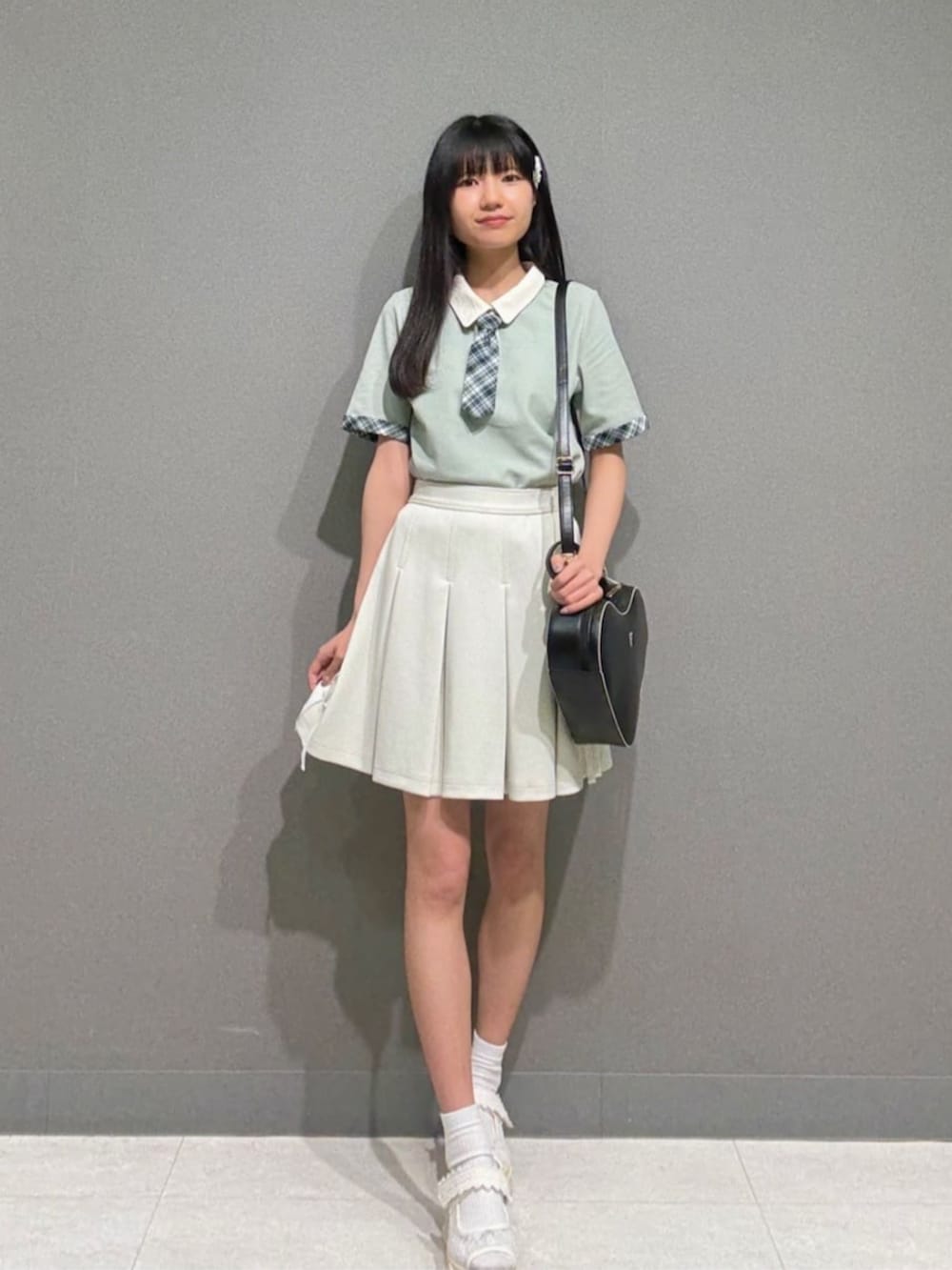 ホワイト系のスカート、ブラック系のハンドバッグ、ホワイト系のサンダルを着用したレディースの夏コーディネートの2枚目の写真