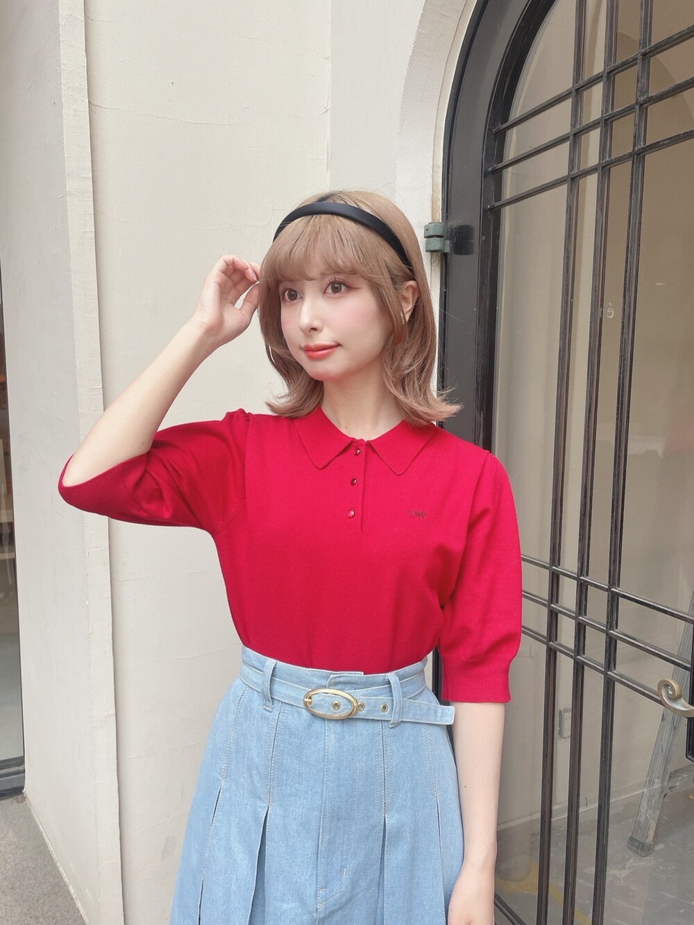 レッド系のポロシャツ、ブルー系のデニムスカート、ブラック系のパンプスを着用したレディースの春コーディネートの2枚目の写真