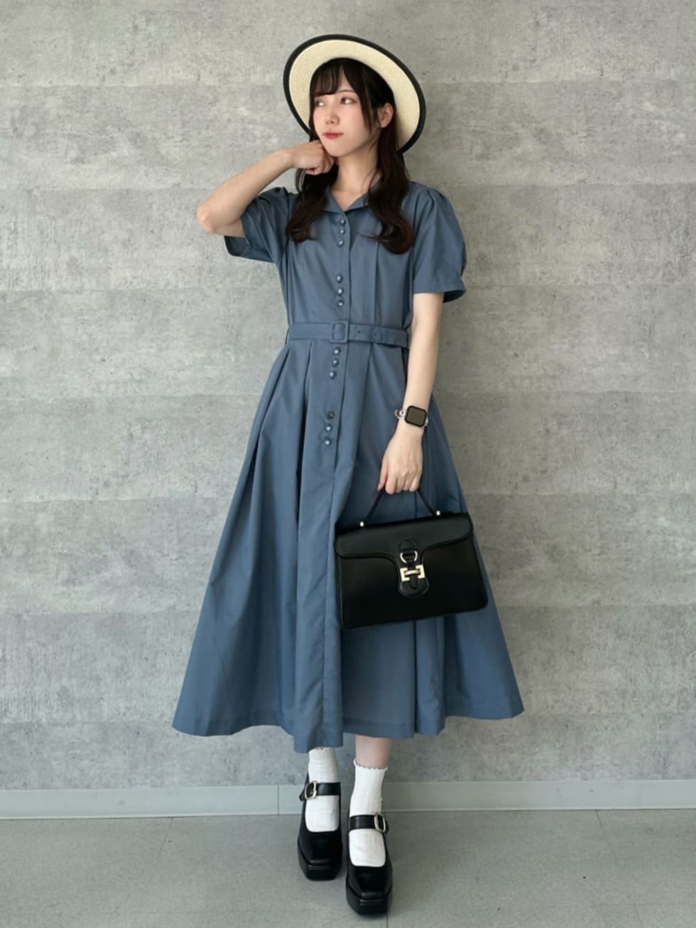 ブラック系のパンプス、ブルー系のシャツワンピース、ブラック系のハンドバッグを着用したレディースの夏コーディネートの3枚目の写真