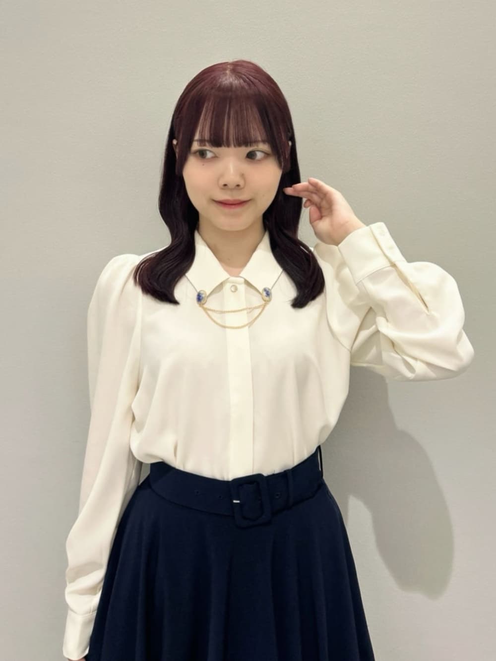 ブルー系のスカート、ブルー系のハンドバッグ、レッド系のパンプスを着用したレディースの秋コーディネートの2枚目の写真