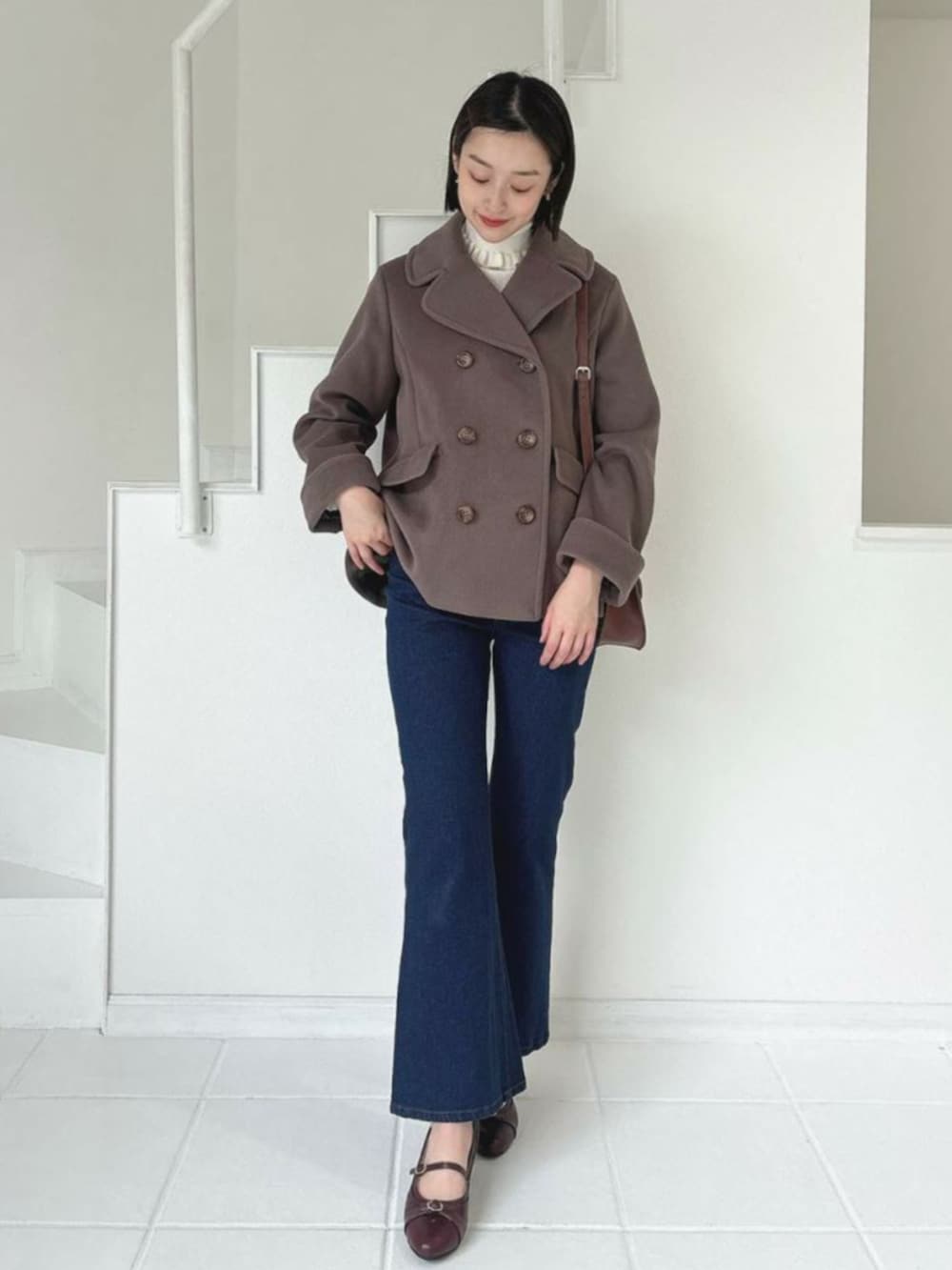 ホワイト系のニット/セーター、ブラウン系のピーコート、ブルー系のデニムパンツを着用したレディースの冬コーディネートの2枚目の写真