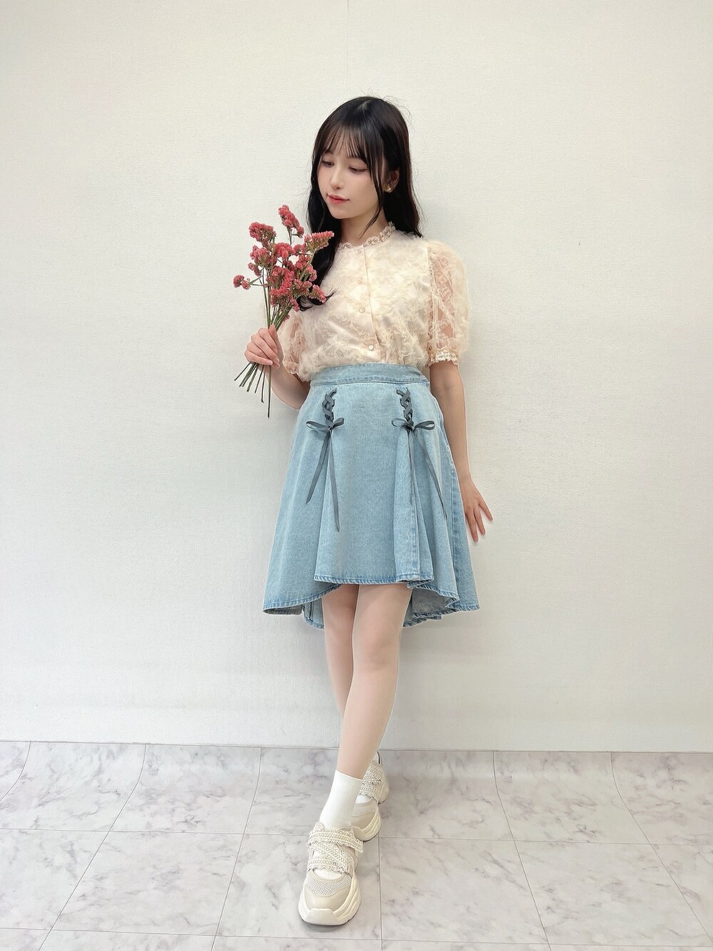 ホワイト系のスニーカー、ピンク系のシャツ/ブラウス、ブルー系のデニムスカートを着用したレディースの春コーディネートの2枚目の写真