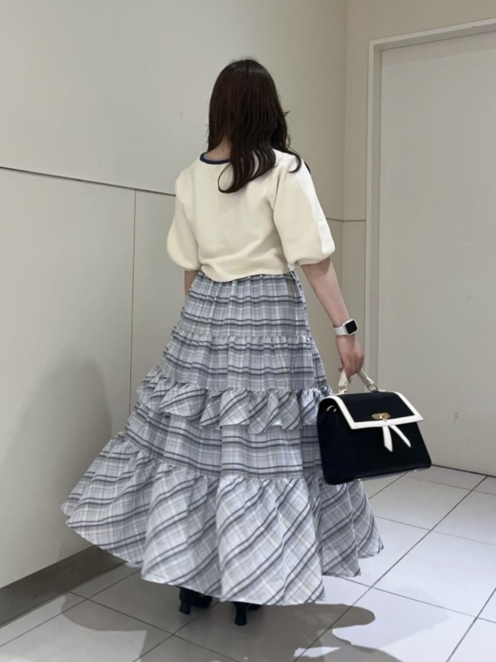 ブラック系のハンドバッグ、ホワイト系のカーディガン/ボレロ、ホワイト系のスカートを着用したレディースの春コーディネートの3枚目の写真