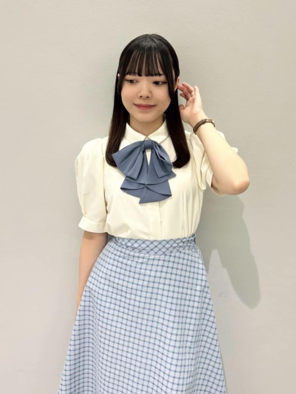 ブルー系のスカート、ブラック系のハンドバッグ、ホワイト系のシャツ/ブラウスを着用したレディースの夏コーディネートの2枚目の写真