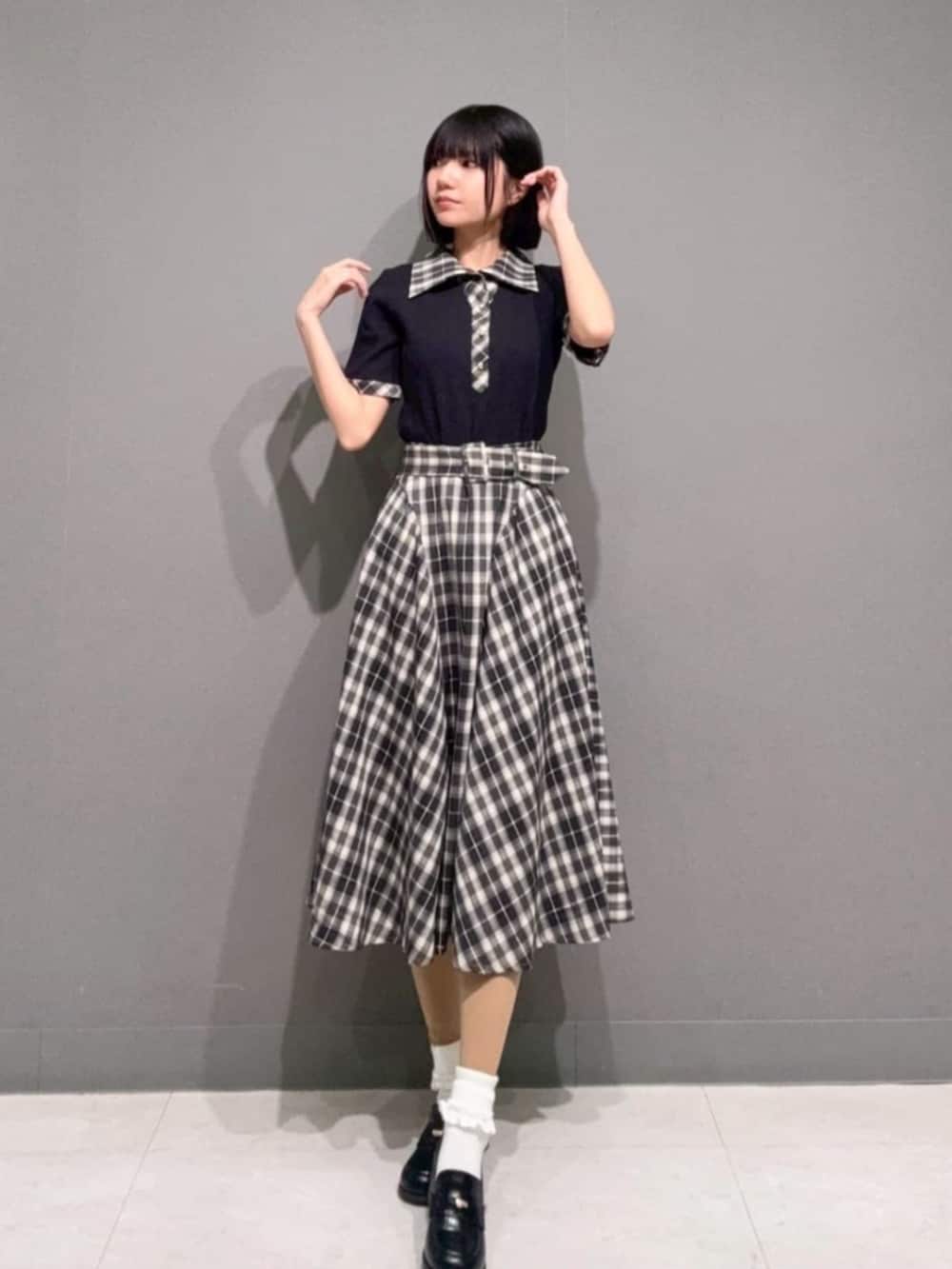 ブラック系のローファー、ブラック系のポロシャツ、ブラック系のスカートを着用したレディースの春コーディネートの2枚目の写真