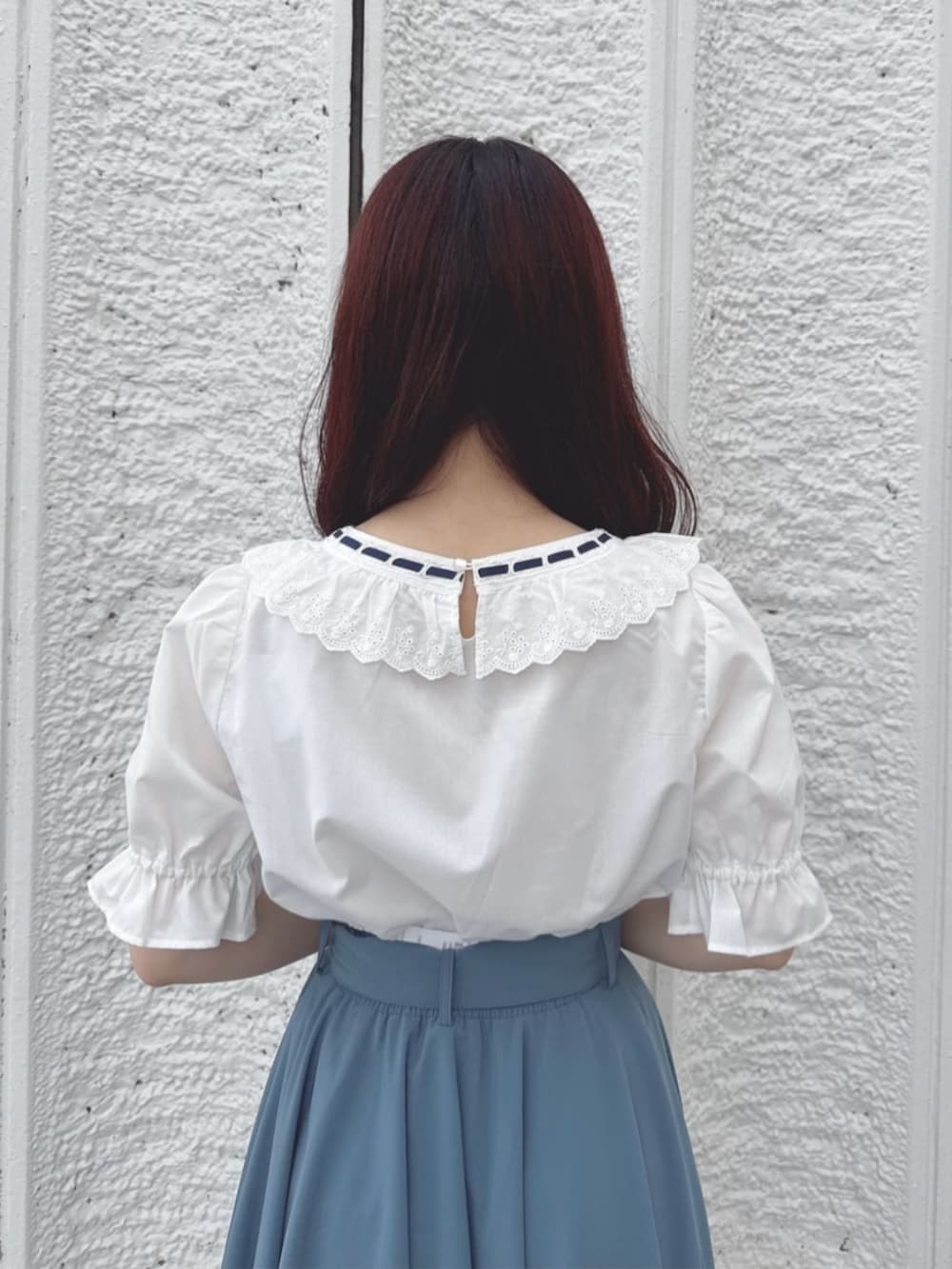 ブルー系のスカート、ホワイト系のパンプス、ホワイト系のハンドバッグを着用したレディースの夏コーディネートの3枚目の写真