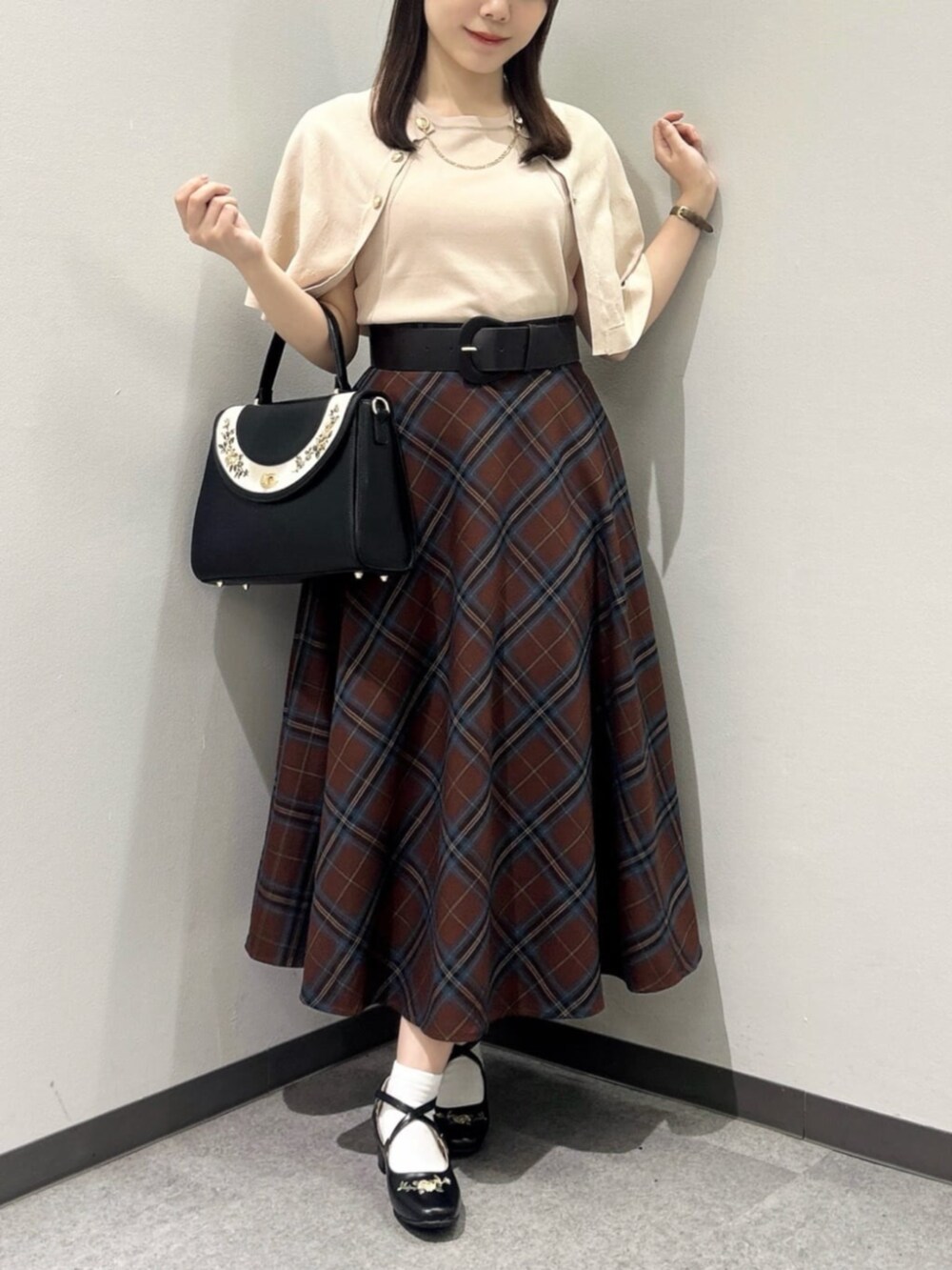 ブラック系のハンドバッグ、ベージュ系のニット/セーター、ブラック系のパンプスを着用したレディースの秋コーディネートの3枚目の写真