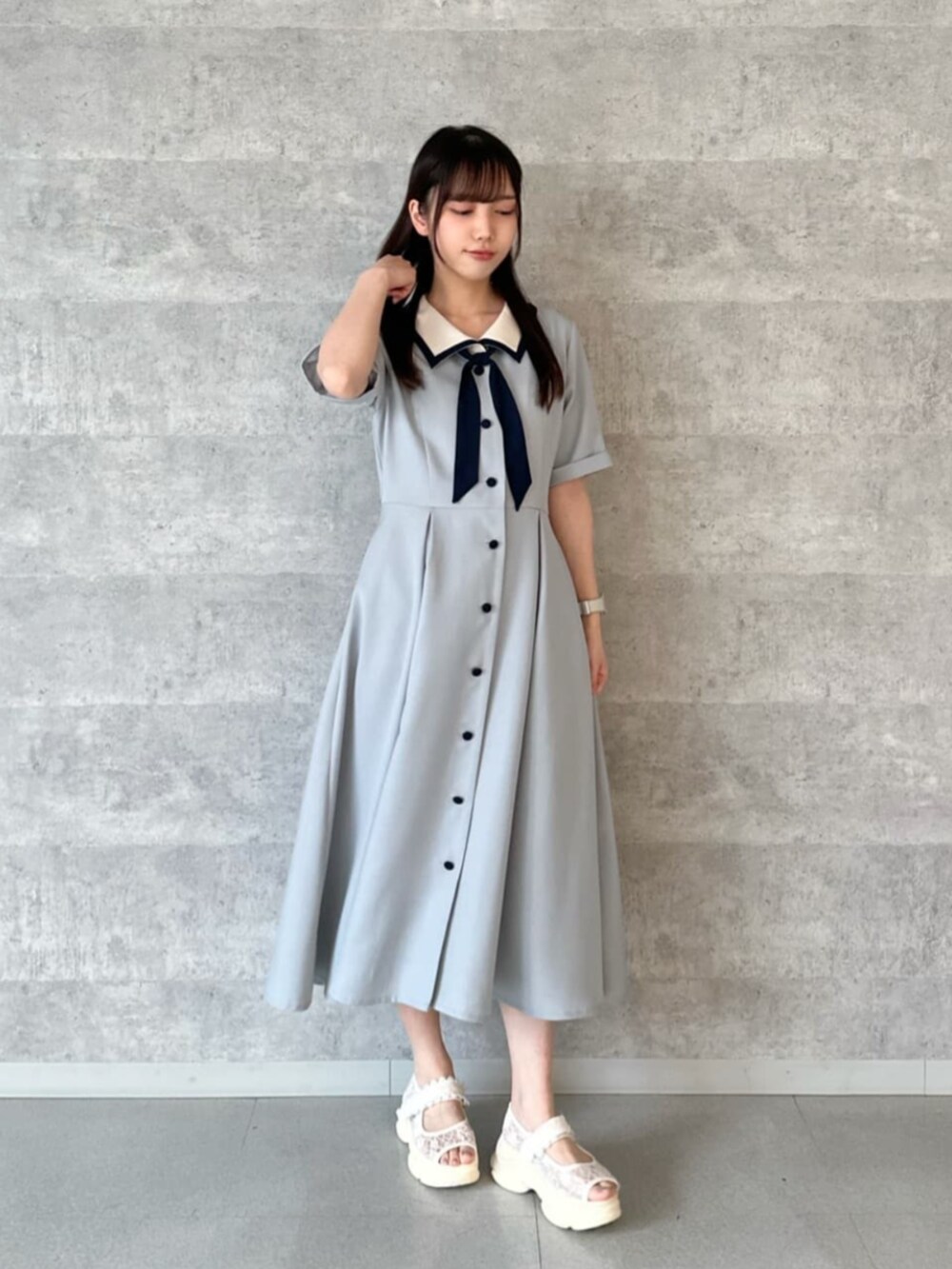 ベージュ系のハンドバッグ、ホワイト系のサンダル、グレー系のワンピースを着用したレディースの夏コーディネートの2枚目の写真