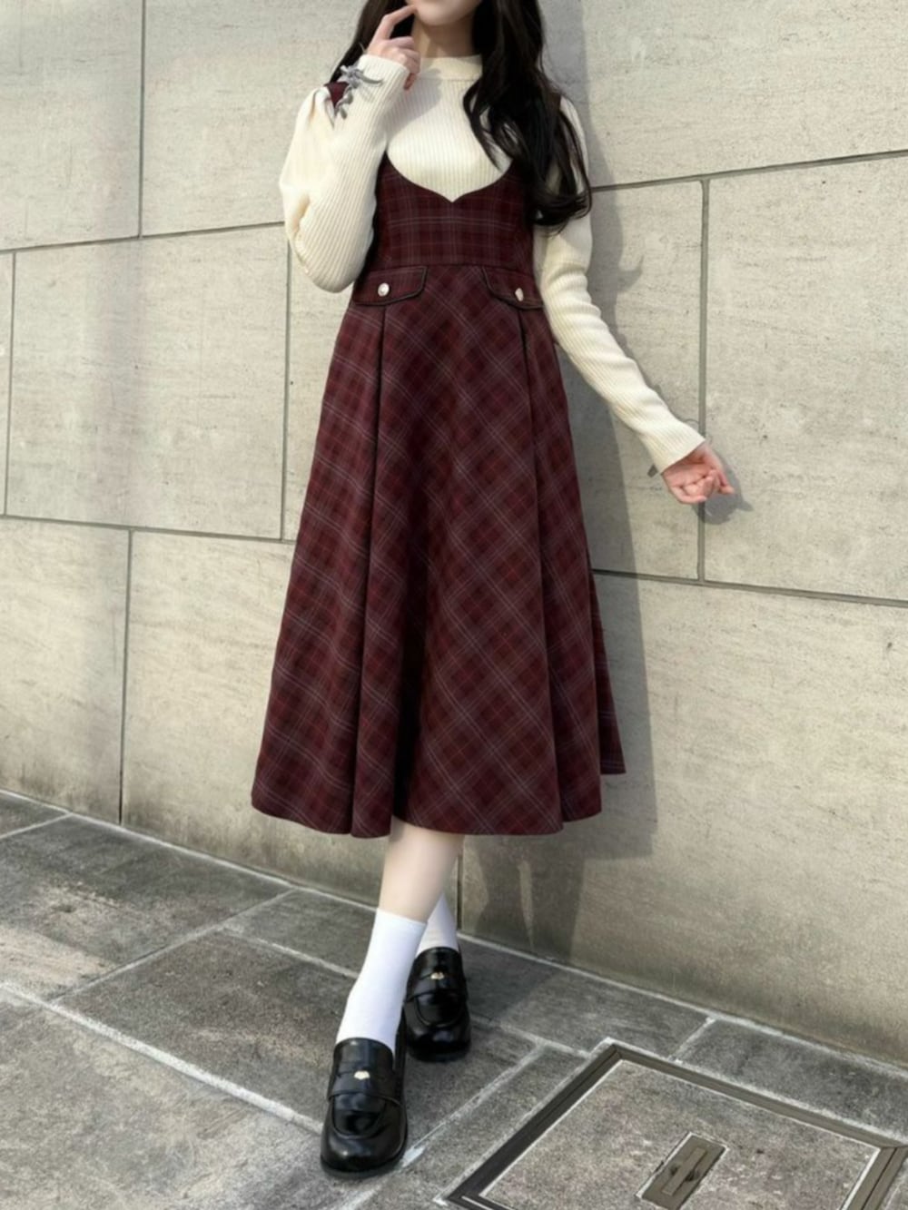 ブラック系のローファー、ホワイト系のニット/セーター、レッド系のジャンパースカートを着用したレディースの冬コーディネートの3枚目の写真