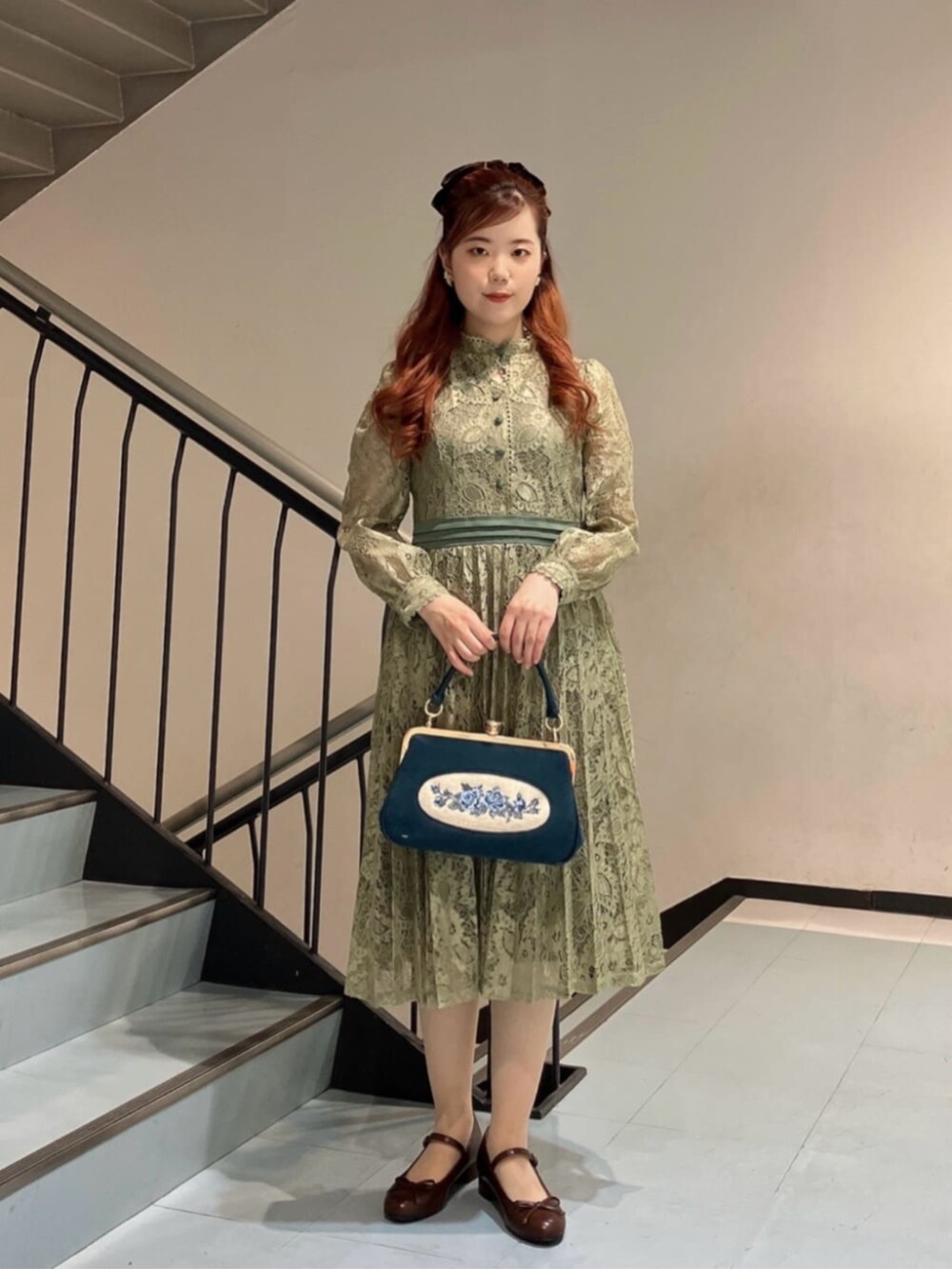 ブルー系のハンドバッグ、ブラウン系のバレエシューズ、グリーン系のドレスを着用したレディースの冬コーディネートの3枚目の写真