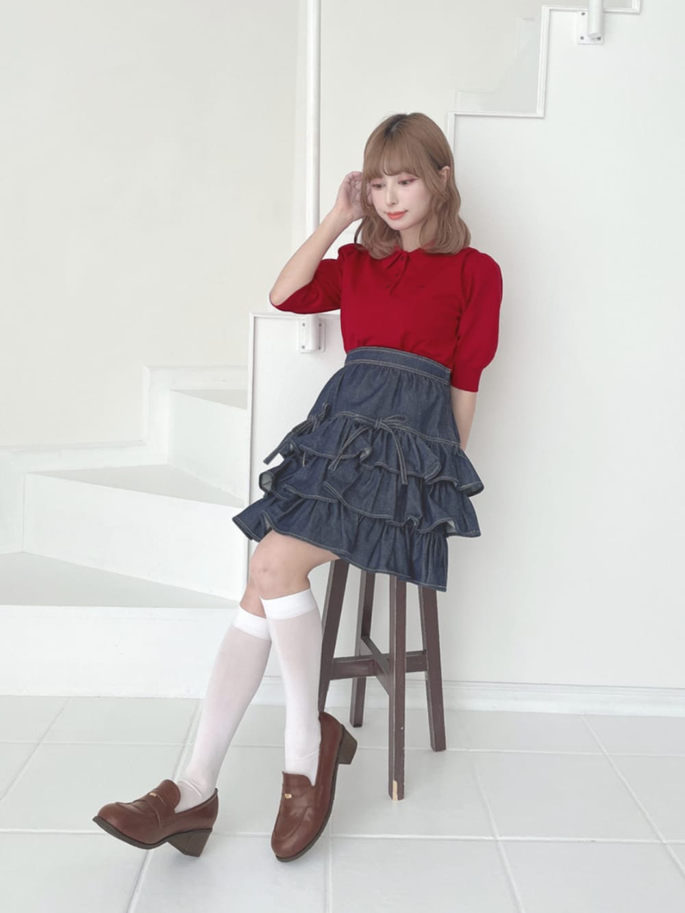 レッド系のポロシャツ、ブラウン系のローファー、ブルー系のスカートを着用したレディースの夏コーディネートの2枚目の写真