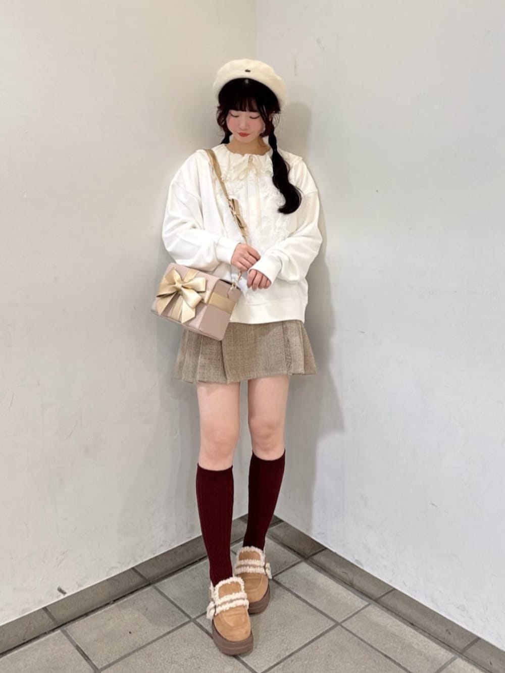 ホワイト系のスウェット、ピンク系のショルダーバッグ、ベージュ系のスカートを着用したレディースの冬コーディネートの3枚目の写真