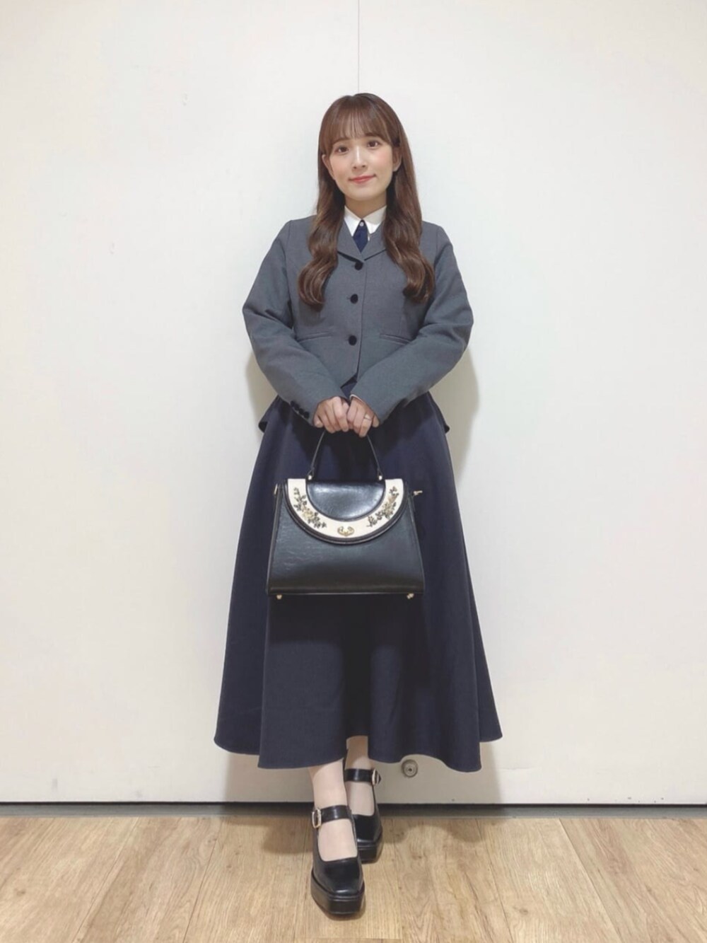 ブラック系のパンプス、ブラック系のハンドバッグ、ホワイト系のシャツ/ブラウスを着用したレディースの秋コーディネートの2枚目の写真