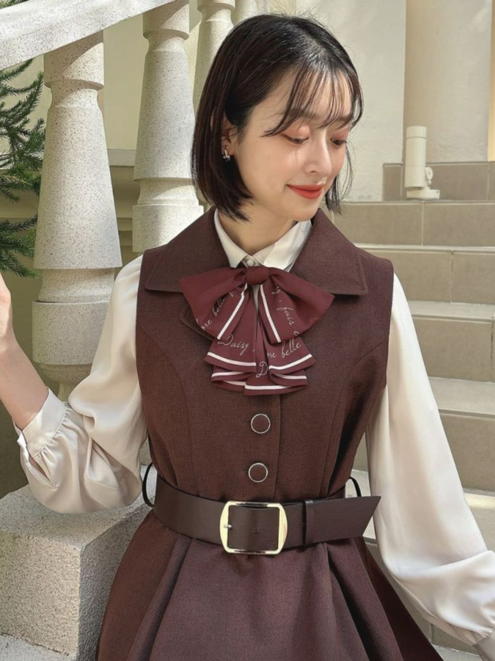 レッド系のパンプス、ブラウン系のワンピース、ベージュ系のシャツ/ブラウスを着用したレディースの秋コーディネートの2枚目の写真