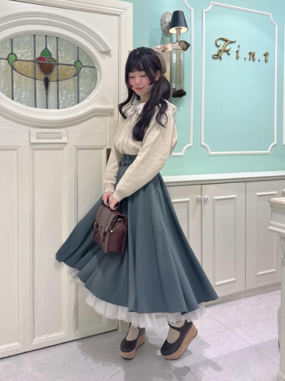 ブラック系のパンプス、グリーン系のスカート、ピンク系のシャツ/ブラウスを着用したレディースの冬コーディネートの2枚目の写真