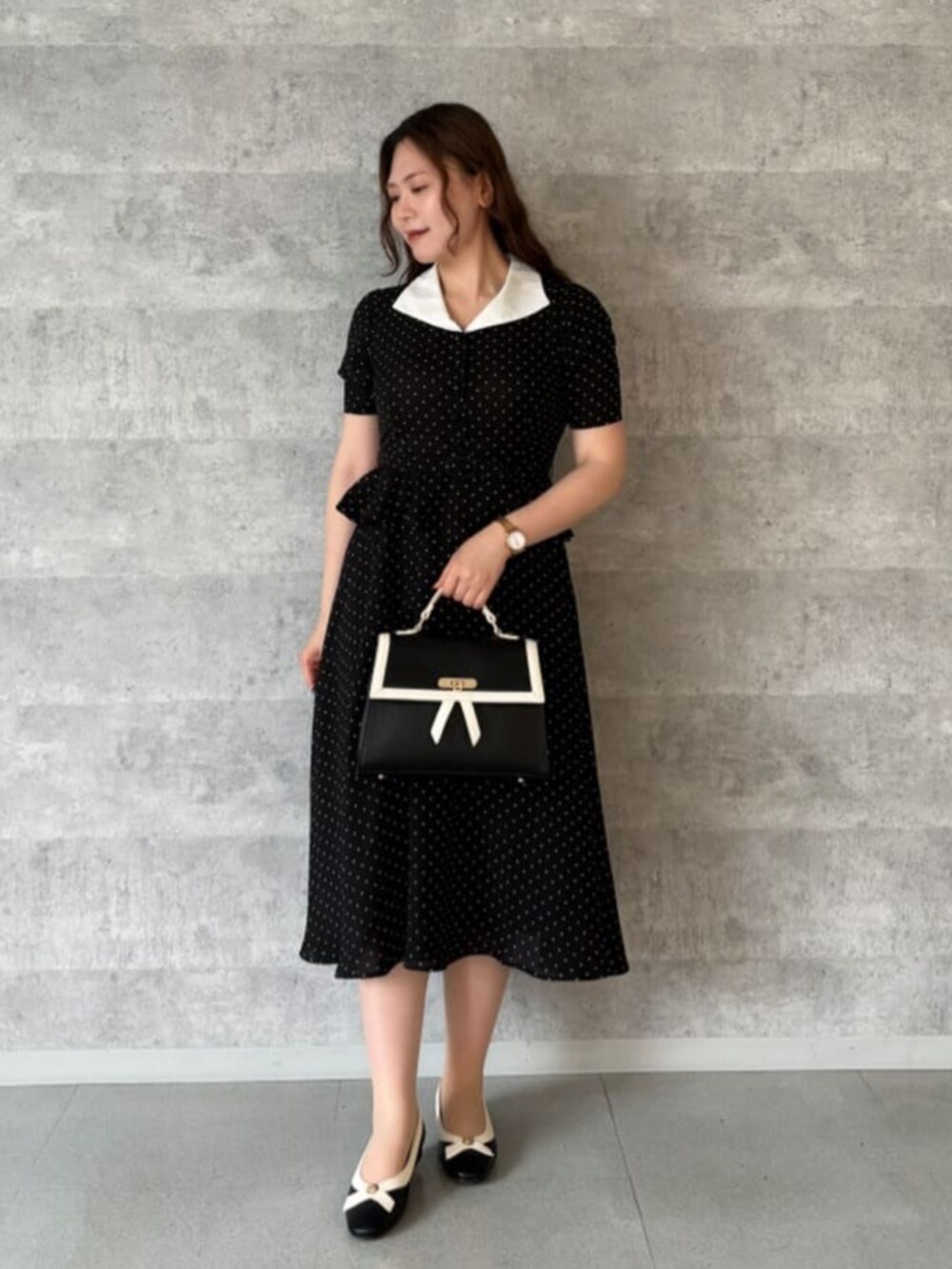 ブラック系のハンドバッグ、ブラック系のパンプス、ブラック系のワンピースを着用したレディースの夏コーディネートの3枚目の写真