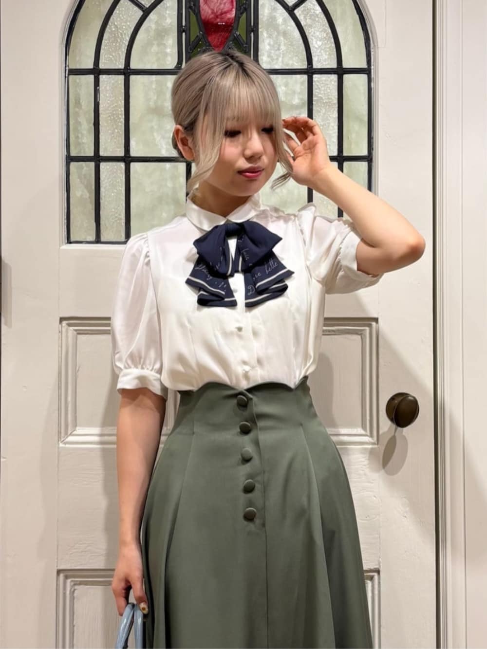 ブラウン系のローファー、ホワイト系のシャツ/ブラウス、グリーン系のスカートを着用したレディースの夏コーディネートの3枚目の写真