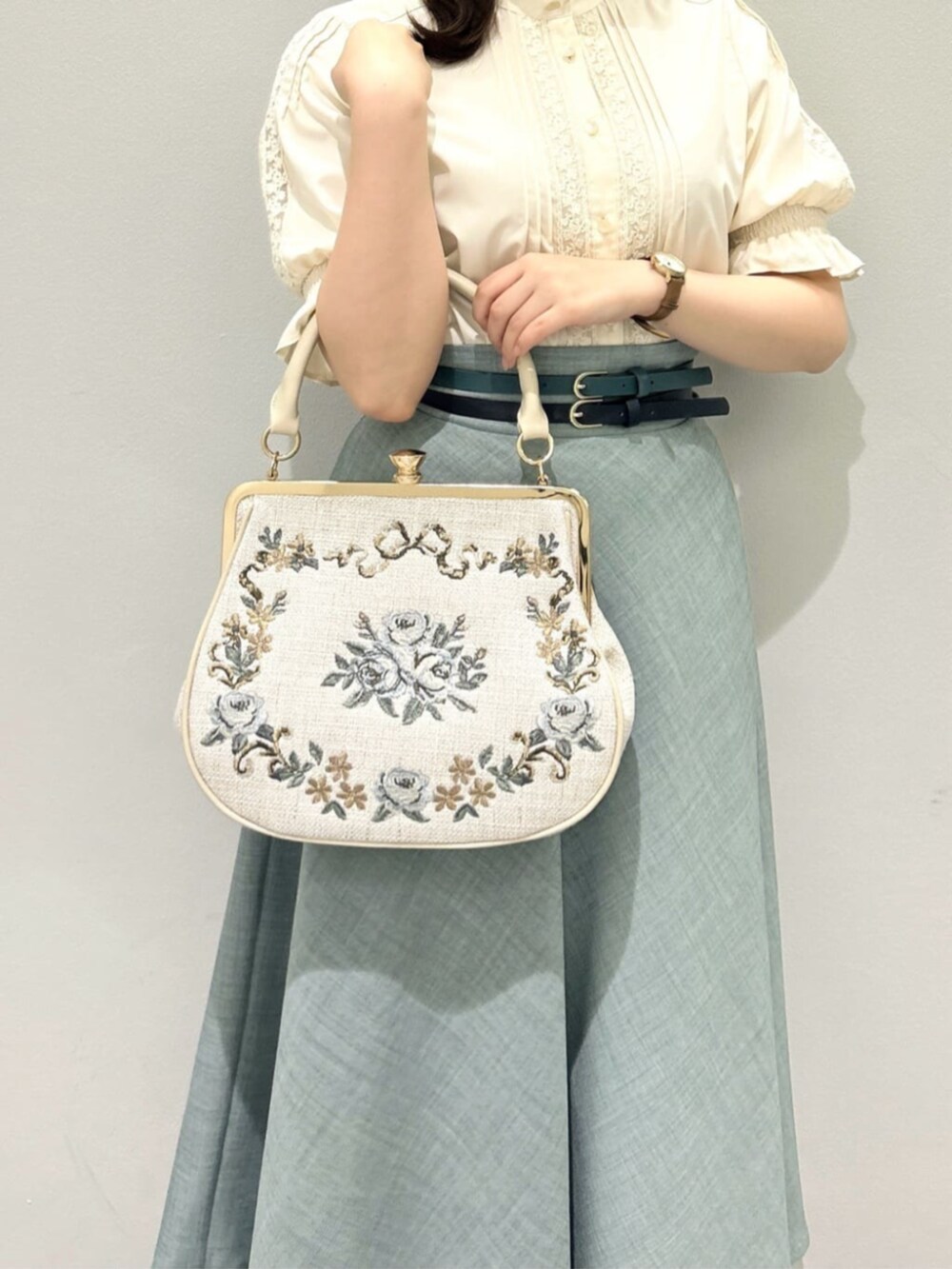 ブラウン系のレインシューズ、ブルー系のスカート、ベージュ系のシャツ/ブラウスを着用したレディースの夏コーディネートの3枚目の写真